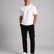 Billionaire by ORVELLA® Luxury White T-Shirt on a male model in a luxury studio photoshoot. Premium white designer T-shirt paired with black tailored trousers and white leather sneakers, showcasing modern British luxury streetwear.