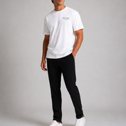 Billionaire by ORVELLA® Luxury White T-Shirt worn by a male model during a professional studio photoshoot. Premium white designer T-shirt styled with black tailored trousers and white leather sneakers, showcasing modern British luxury streetwear with a refined minimalist aesthetic.
