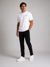 Billionaire by ORVELLA® Luxury White T-Shirt worn by a male model during a professional studio photoshoot. Premium white designer T-shirt styled with black tailored trousers and white leather sneakers, showcasing modern British luxury streetwear with a refined minimalist aesthetic.