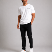 Billionaire by ORVELLA® Luxury White T-Shirt worn by a male model during a professional studio photoshoot. Premium white designer T-shirt styled with black tailored trousers and white leather sneakers, showcasing modern British luxury streetwear with a refined minimalist aesthetic.