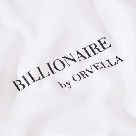 Close-up of the Billionaire by ORVELLA white luxury T-shirt chest print, showing refined black branding on smooth premium fabric.
