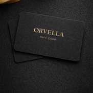 Orvelia gift card on a dark textured surface with a gold ribbon.