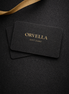 Orvelia gift card on a dark textured surface with a gold ribbon.