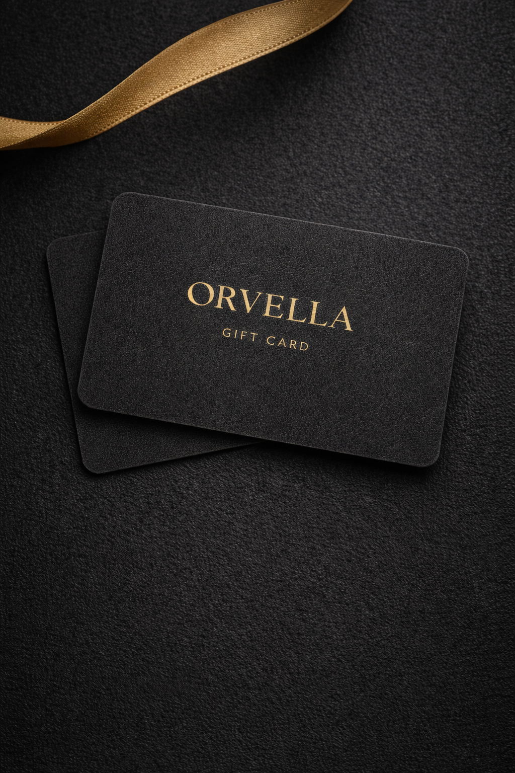 Orvelia gift card on a dark textured surface with a gold ribbon.