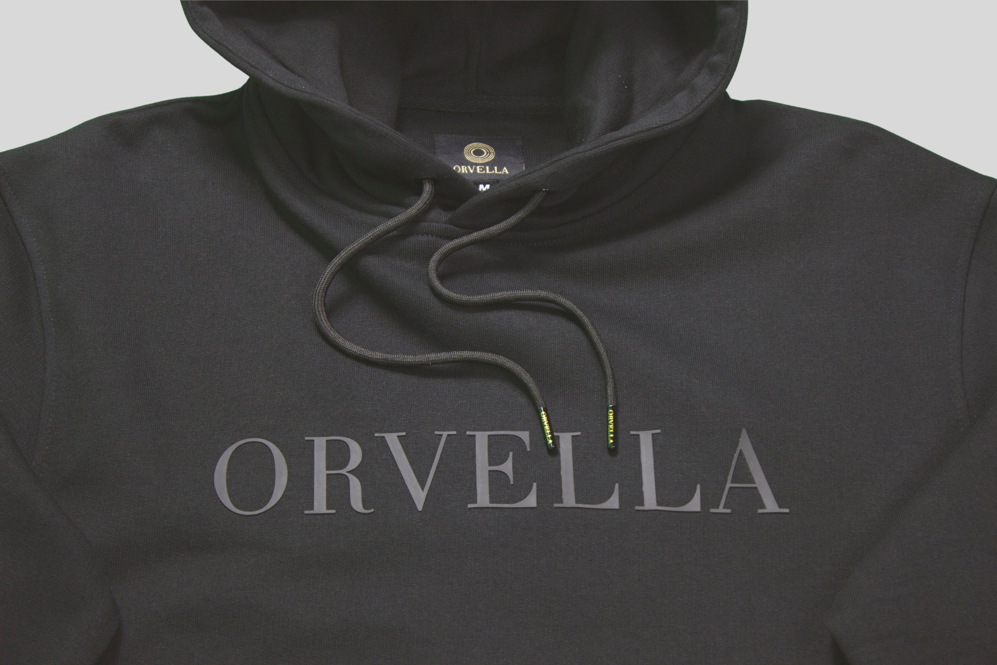 Luxury black ORVELLA hoodie close-up with tonal chest logo, premium drawstrings and branded aglets
