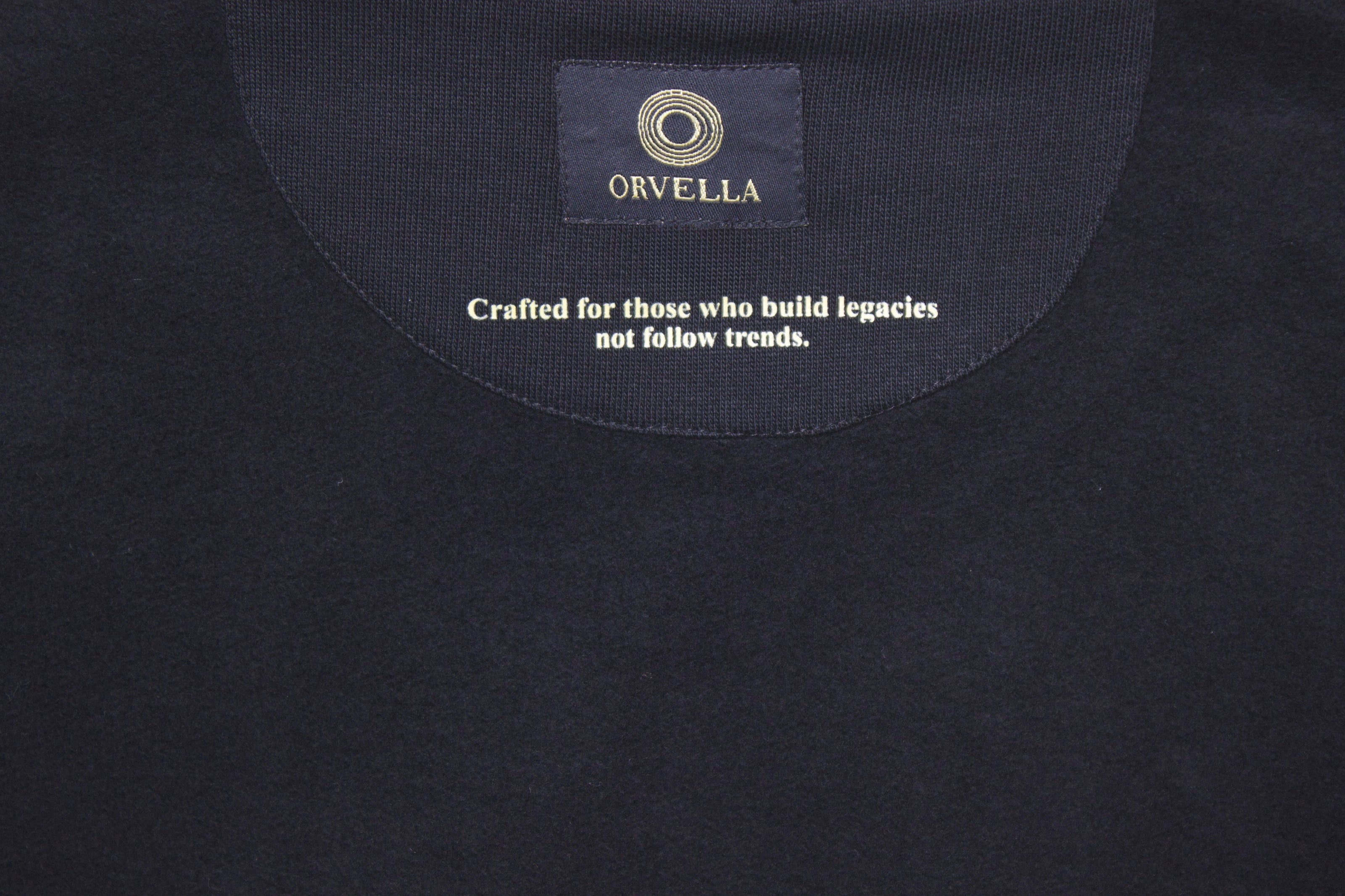 Inside neckline detail of black ORVELLA hoodie with branded label and motivational quote