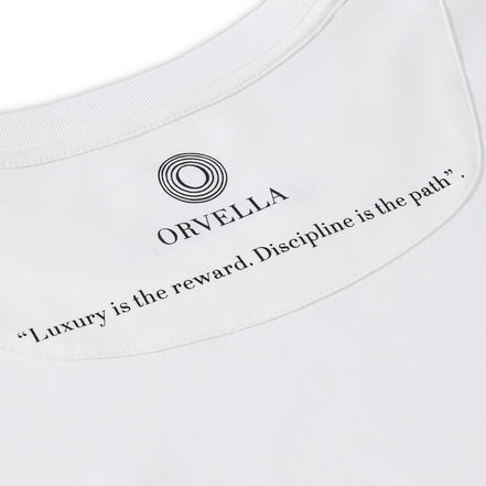 Close-up of the Billionaire by ORVELLA white luxury T-shirt inner neck print, showing the ORVELLA logo, clean collar stitching, and the quote “Luxury is the reward. Discipline is the path.”