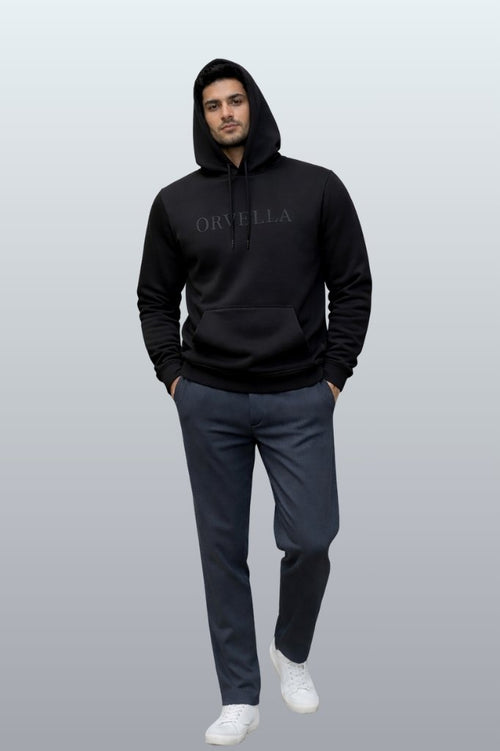 Male model wearing ORVELLA signature jet black hoodie with embossed logo