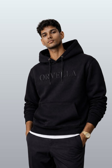 Man wearing a black hoodie with 'Orvella' branding against a plain background